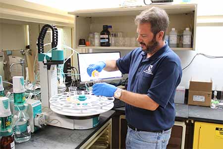 Man working in a lab, pouring liquid into a test tube.