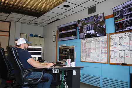 One man sitting at a desk with two large screens in the background monitoring work at the water plant