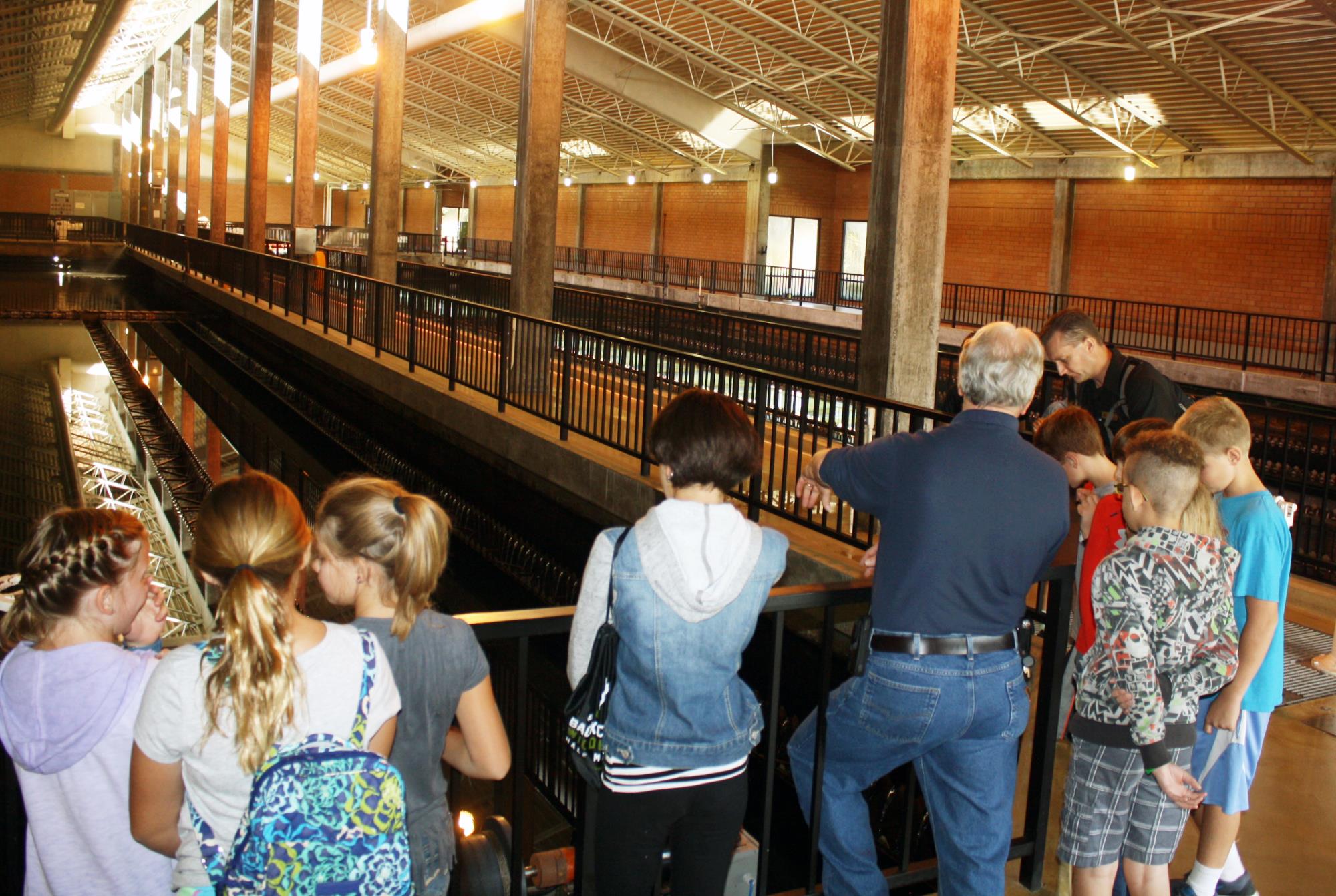 Group of students listening to Centennial Water staff member standing in the floculation and sedimentation building at the Water Treatment Plant.