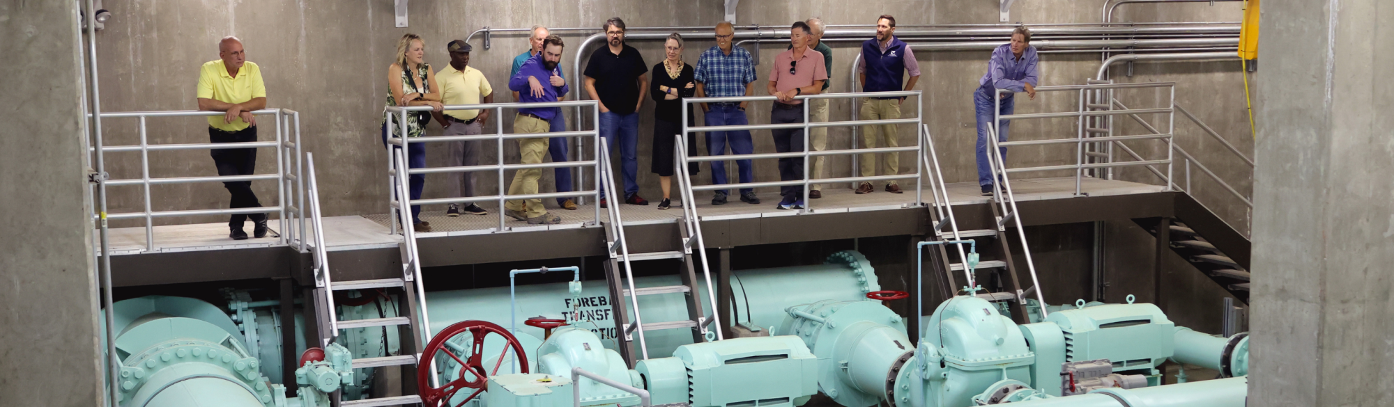 Group of people standing on platform looking over Centennial Water's pump station.